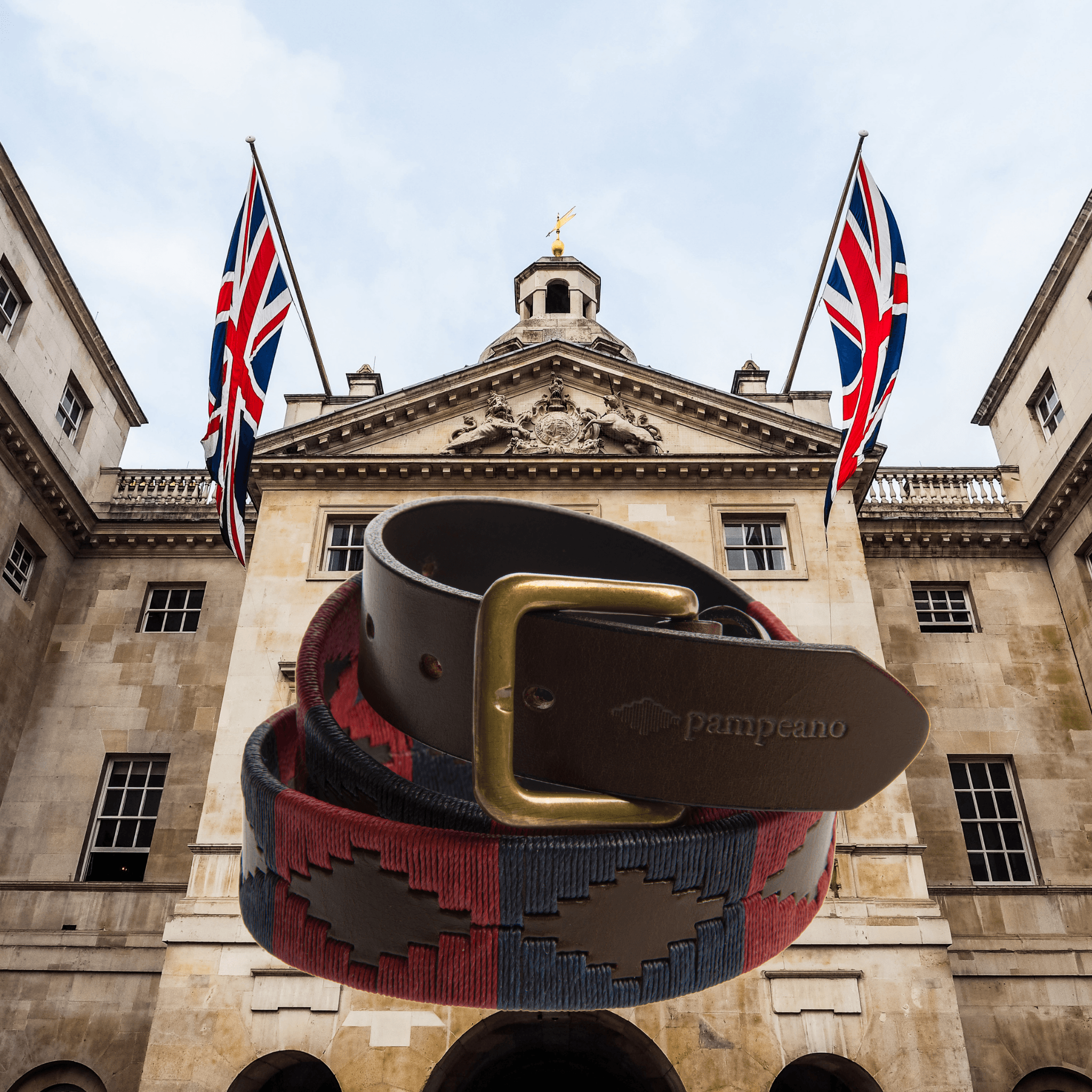 The Country Direct & Pampeano Household Division Leather Polo Belt, made with premium brown leather, with red and navy thread detailing, and Palace in the background. 